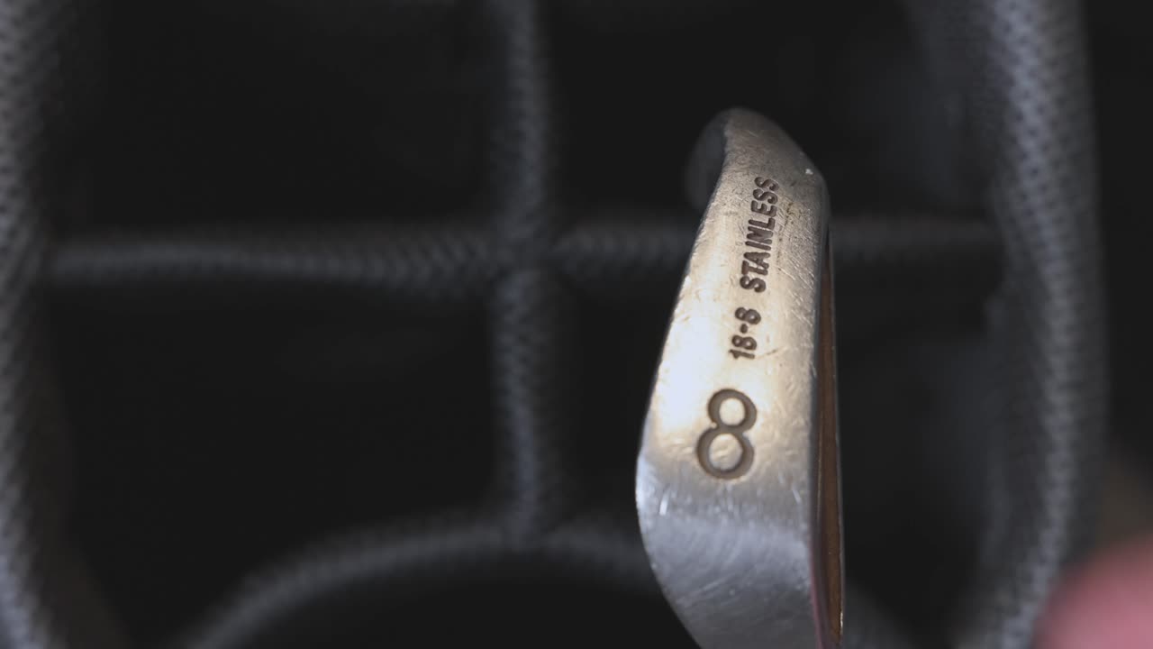 close-up shot of a 8 iron being returned back into a golf bag after being used
