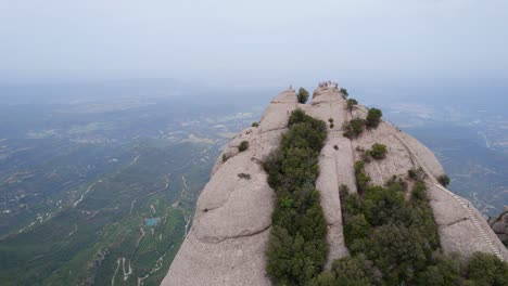 tourists at the summit of montserrat mountain under grey sky due to air pollution and climate crisis, spain