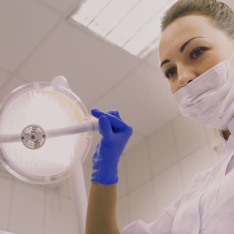 a dentist turns the lamp towards the patient