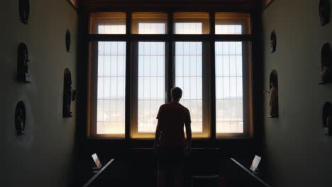 Silhouette-Of-Man-Looking-Out-The-Window-Of-A-Museum