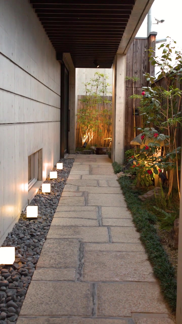 Immagine statica di un sentiero in pietra tra muri di cemento con illuminazione calda da giardino a Kyoto