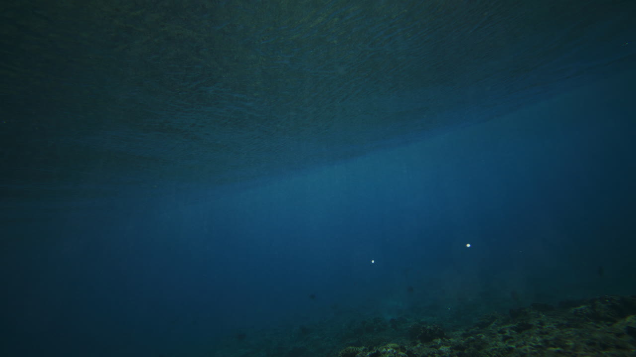 Swim below along coral reef as strong ocean wave crashes with vortext spinning white wash turbulent foam
