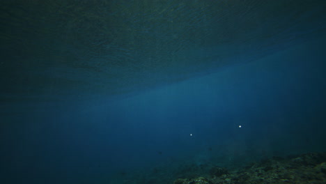 Swim-below-along-coral-reef-as-strong-ocean-wave-crashes-with-vortext-spinning-white-wash-turbulent-foam