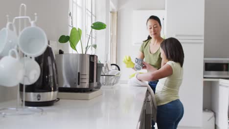 video of happy asian mother and daughter cleaning kitchen