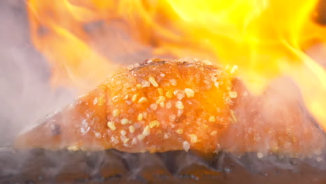 a close up side shot of barbecue fish flambe with gin pouring over it in slow motion