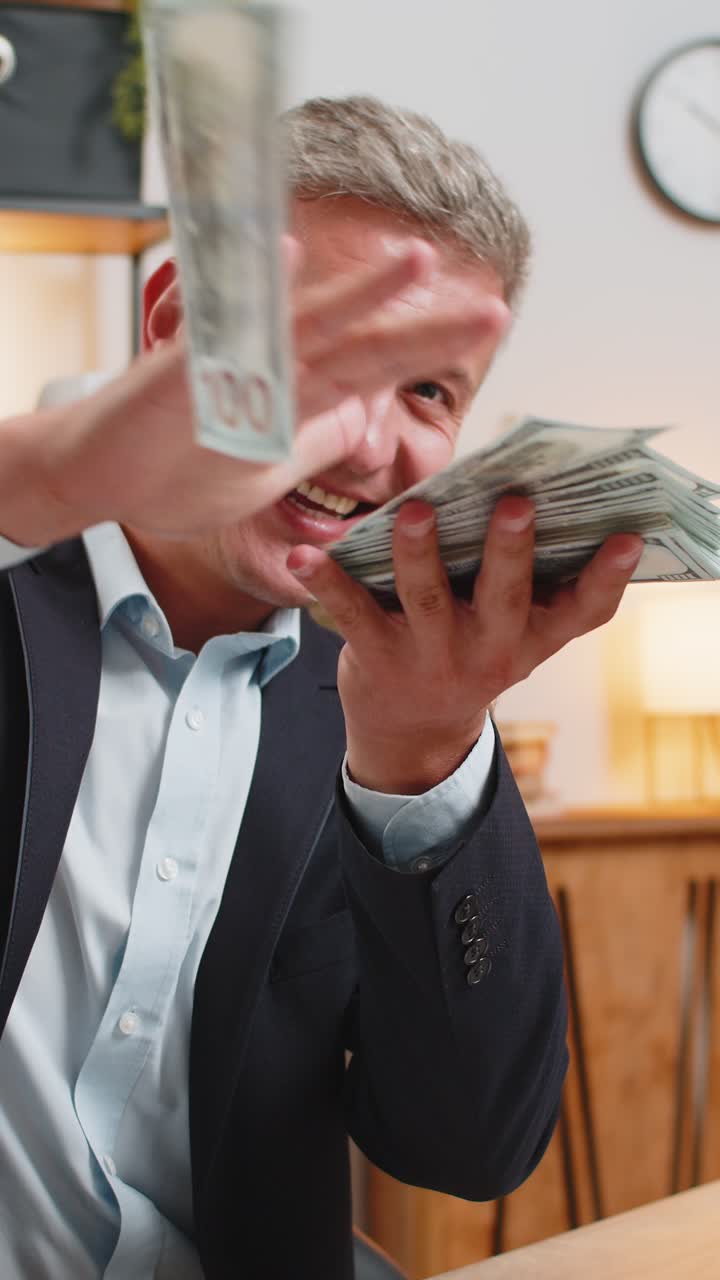 Um jovem empresário rico e feliz com um fato formal a desperdiçar dinheiro na secretária do escritório.