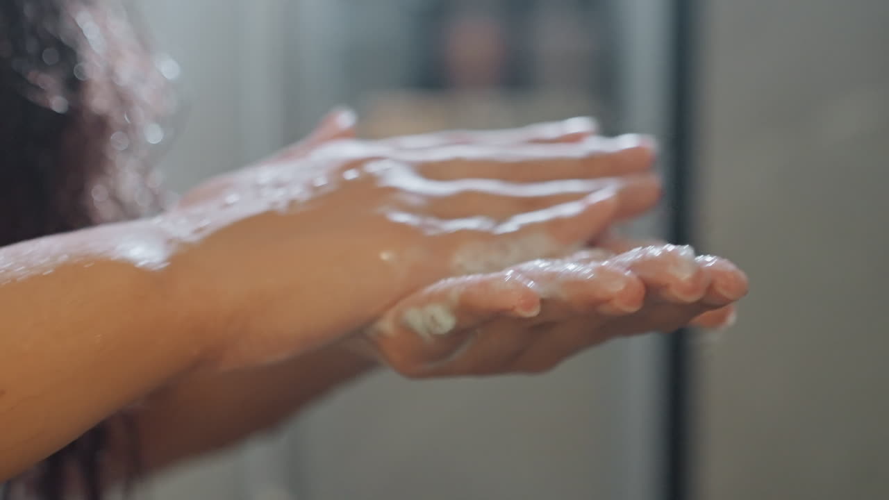 Hotel sink guest lathering hands with foam, closeup of palms creating suds, water dripping from fingers, hygiene and amenity focus for hospitality or wellness campaign, calming modern bathroom