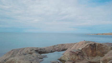 Eine-Person-Schwimmt-Von-Einer-Felsigen-Küste-Ins-Offene-Meer-Und-Zum-Horizont