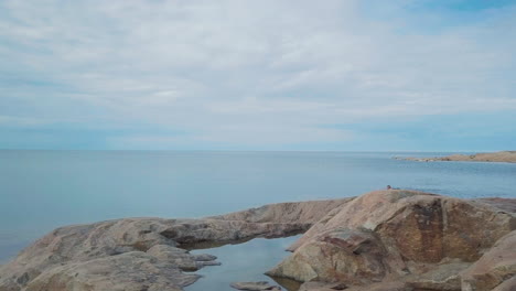 una persona nada desde la costa rocosa hacia el mar abierto y el horizonte