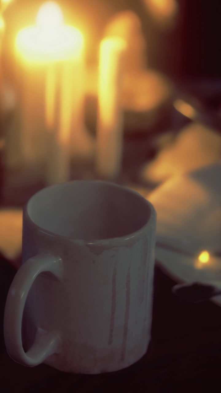 Ambiente a lume di candela con una tazza e del cibo su un tavolo di sera.