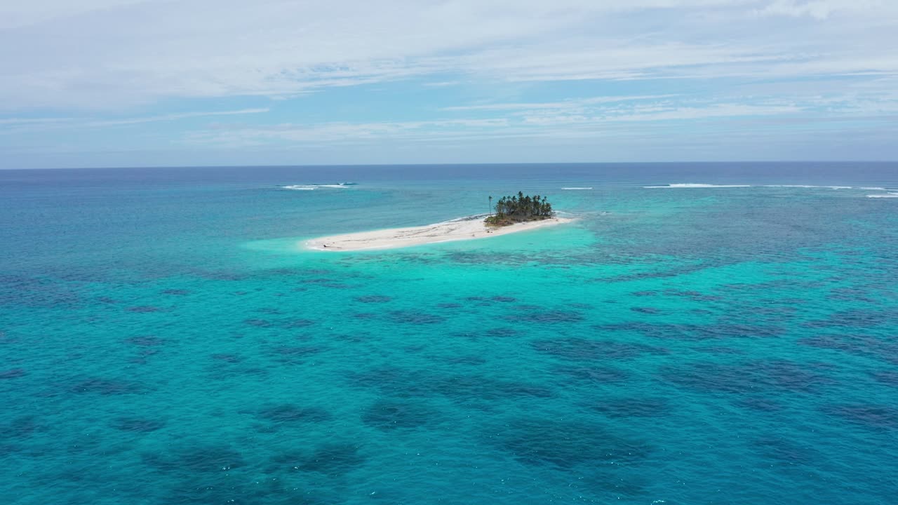 Aerial View of Small Coral Island and Turquoise Ocean Water