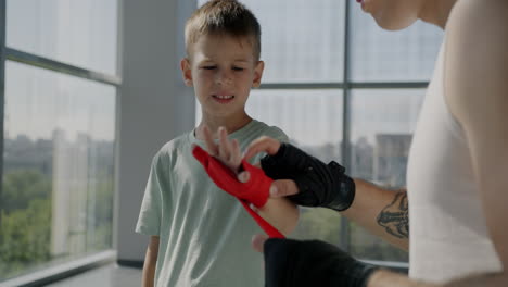 boy learning to wrap his boxing hands
