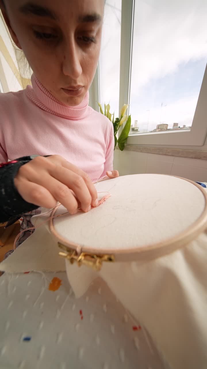 Giovane donna concentrata su un progetto di ricamo punch needle