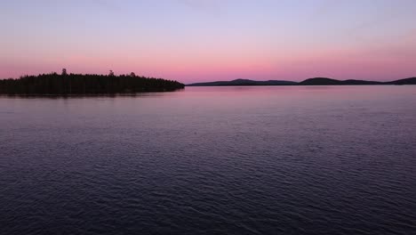 Picturesque-evening-dusk-blue-hour-aerial-over-calm-lake-in-Sweden