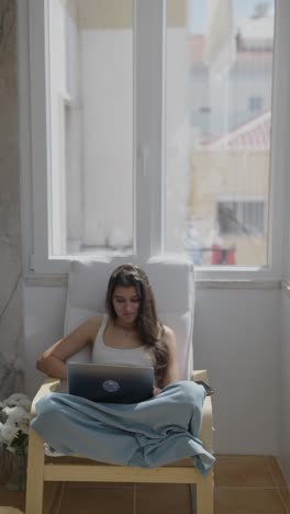 mujer trabajando en una computadora portátil en el balcón