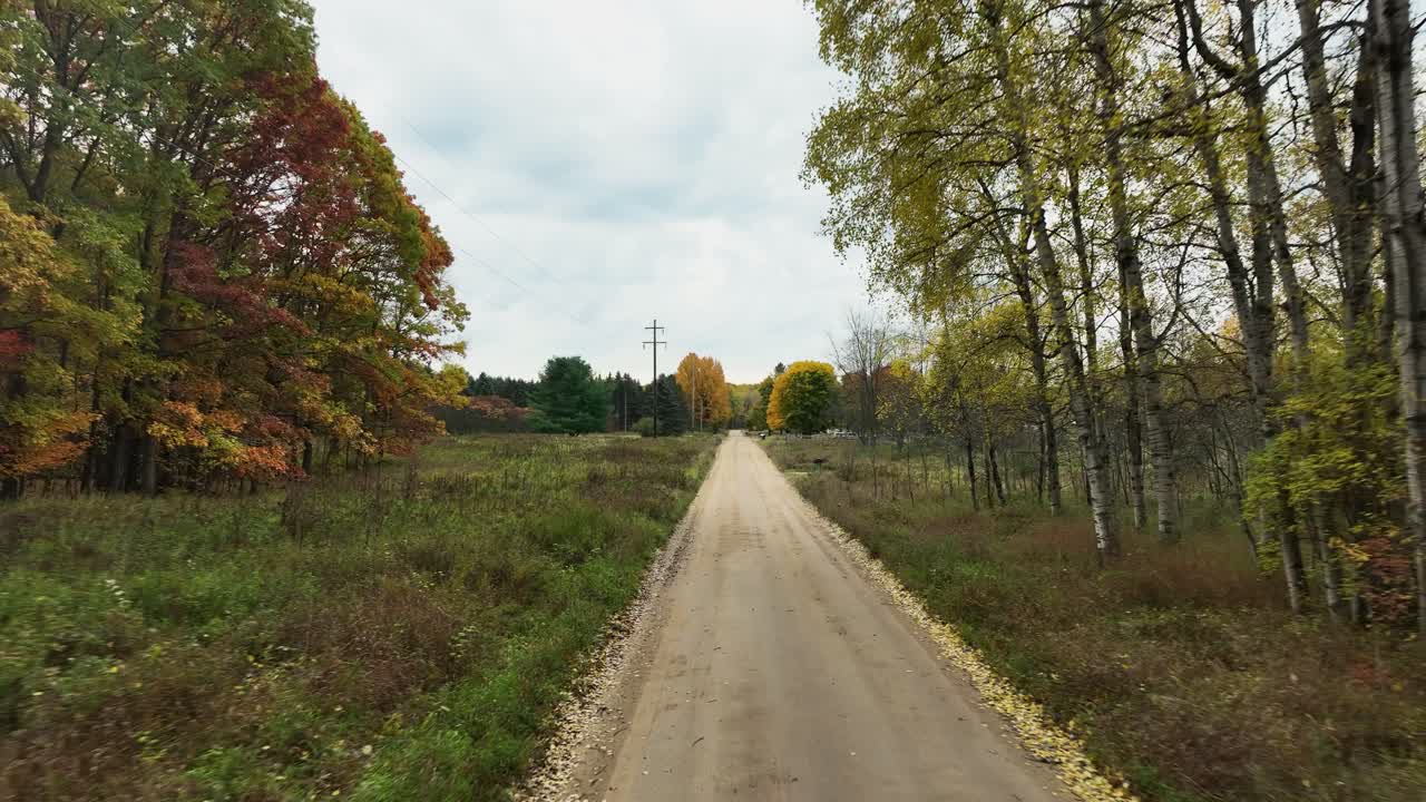 camino de campo, sin pavimentar y fangoso, a los árboles de color otoño cercanos