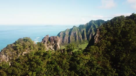 Drohnenaufnahme-Schwenkt-Und-Enthüllt-Die-Zerklüfteten-Gipfel-Einer-Hawaiianischen-Bergkette,-Im-Hintergrund-Ist-Die-Kualaoua-Ranch-Zu-Sehen