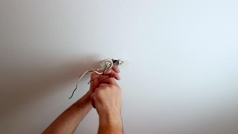 fije un tornillo en un soporte de luz de techo con cables que cuelgan de un agujero