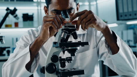 a person in a lab coat looks through a microscope in a laboratory