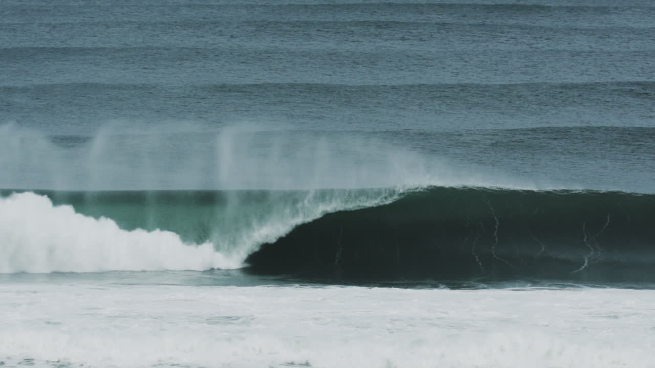 Shallow break with wide curling wave and sea foam crashing in frame