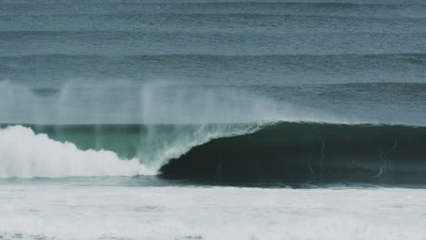 shallow break with wide curling wave and sea foam crashing in frame