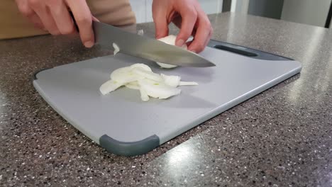 cerca de un chef caucásico picando cebolla en una tabla de cortar