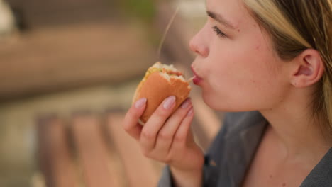 close-up of someone taking a bite of shawarma, focusing on the hand holding the sandwich and the moment of eating, with a blurred background in an outdoor setting