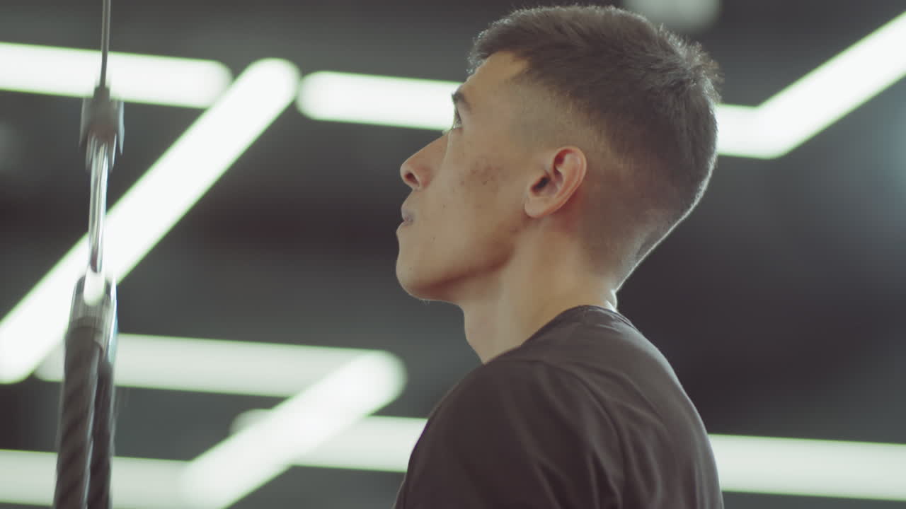 человек делает стоящие пульдоны с кабельной машиной в спортзале