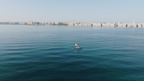 Aerial-footage-rotating-around-a-fishing-boat-just-outside-of-Old-City-Bari,-Italy-in-the-morning