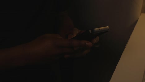 black male texting on phone in dark home office