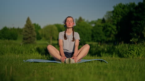 a young woman sits on her yoga mat, her face deeply relaxed as she absorbs the exceptional energy of the golden sun. smooth rightward camera movement capturing the moment.