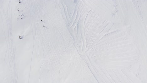 aerial top down shot of two people walking on snowy road up the mountain