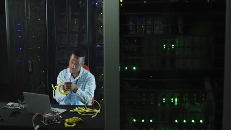 técnico de computadoras afroamericano trabajando en una sala de servidores de negocios.