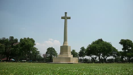 hd static shot of world war two memorial graveyard with tall crucifix monument in a peaceful cemetery in kanchanaburi, thailand