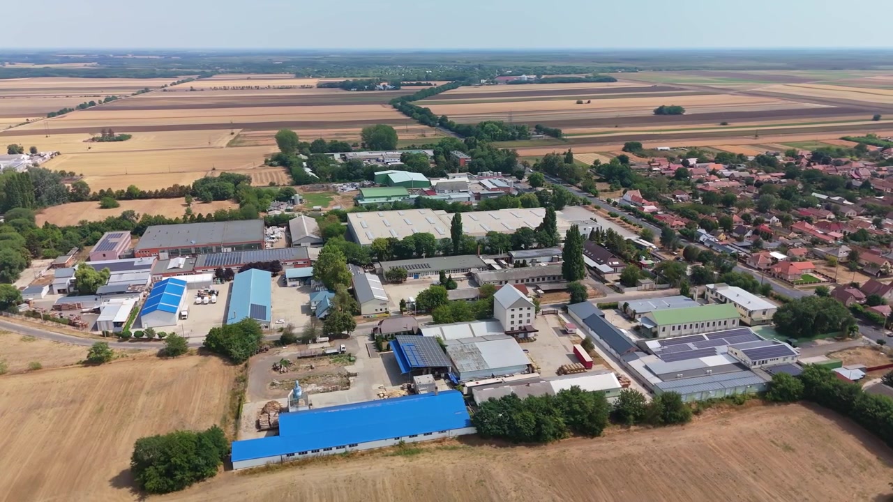 Panorama aereo estivo dell'area industriale di Hajdúböszörmény, in Ungheria, con edifici di fabbriche, magazzini e strade accanto a quartieri residenziali, campi e terreni agricoli