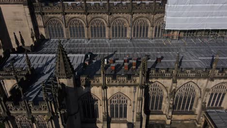 aerial drone flight alonside manchester cathedral showing off its gothic architecture and bee hives on the rooftop