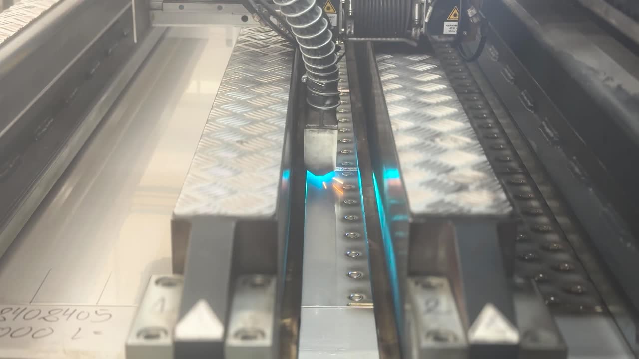 Industrial laser machine welding metal, a robotic mechanism in a factory. Technology concept. A flat sheet of stainless steel is being welded with flashes. Front view. Type D