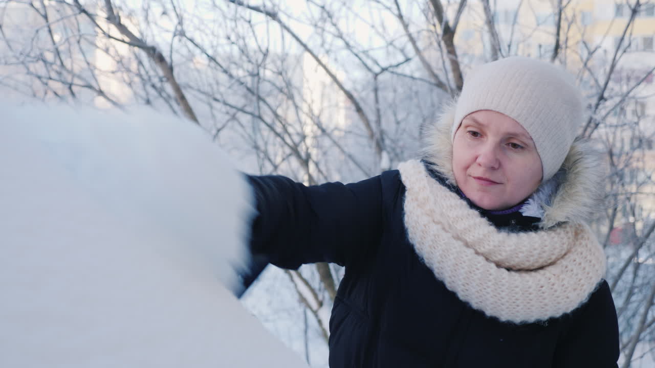 женщина убирает снег со своего автомобиля