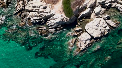 Overhead-clip-over-the-rocks-of-an-exotic-beach-in-Vourvourou,-Haklidikin-in-northern-Greece-on-a-clear-summer-day