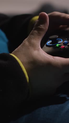 video vertical de cerca manos hombre jugando controlador de videojuego sentado sofá en casa 1