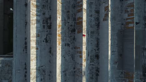 Man-in-red-shirt-enjoying-morning-sun-laying-on-old-industrial-roof,-aerial