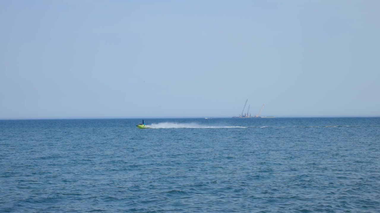 Jetskiing Over The Calm Blue Sea On A Sunny Day Against The Bright Blue Sky. - wide shot