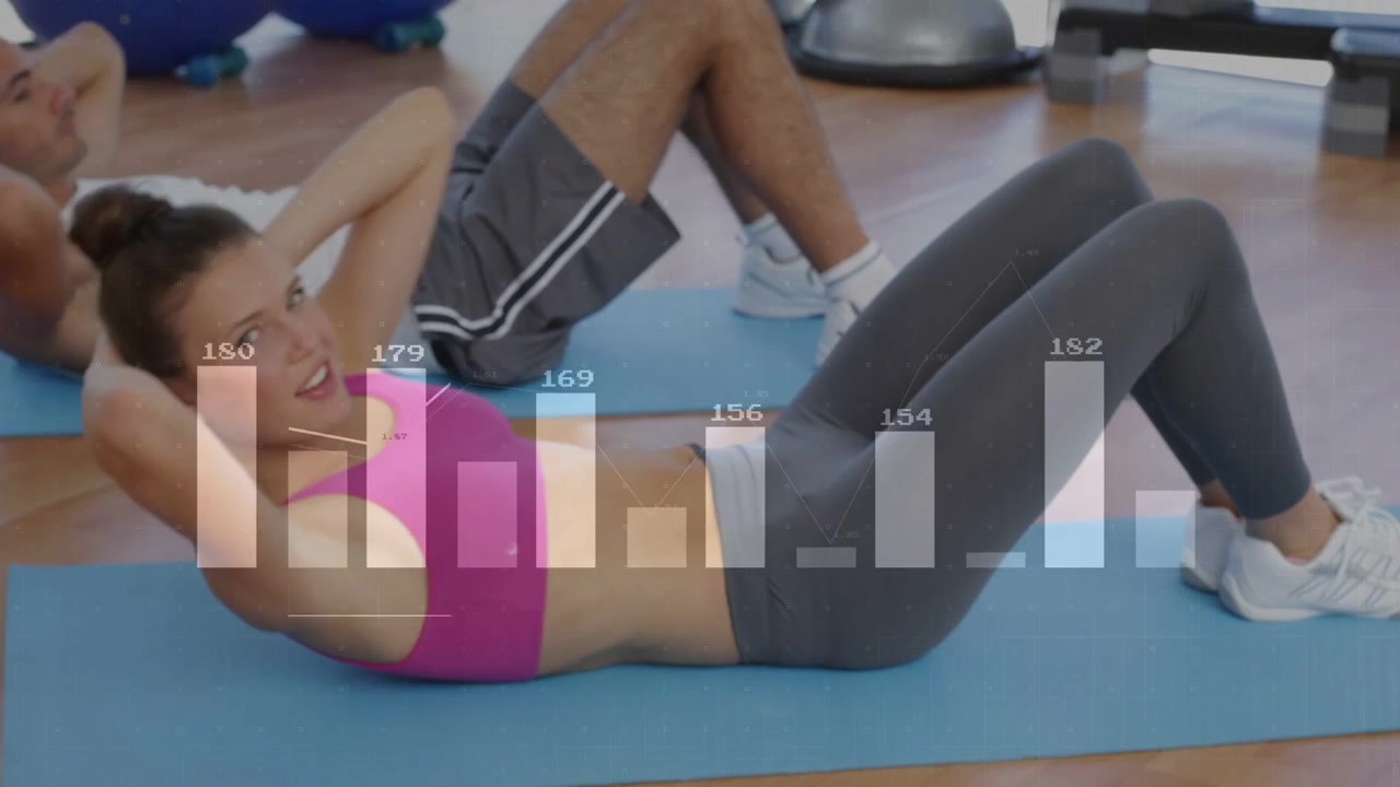 A la señal del instructor, una mujer con camiseta sin mangas gris realizando abdominales en un gimnasio, con gráficos registrando el esfuerzo