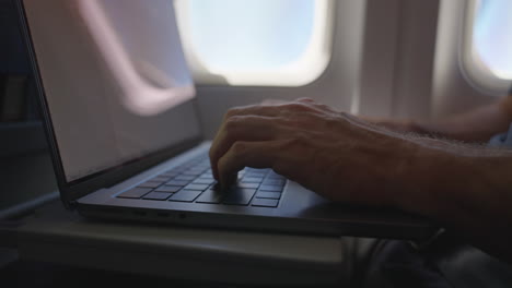 hombre o hombre de negocios escribiendo y usando computadora o portátil durante el vuelo