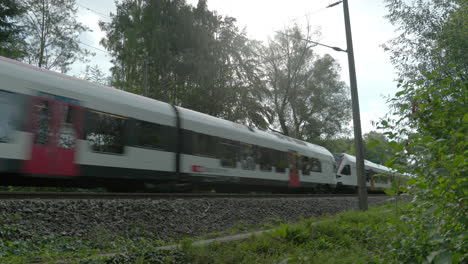 El-Tren-Blanco-Y-Rojo-Pasa-En-Un-Entorno-Natural,-Región-Rural-Con-Mucha-Naturaleza-Verde.