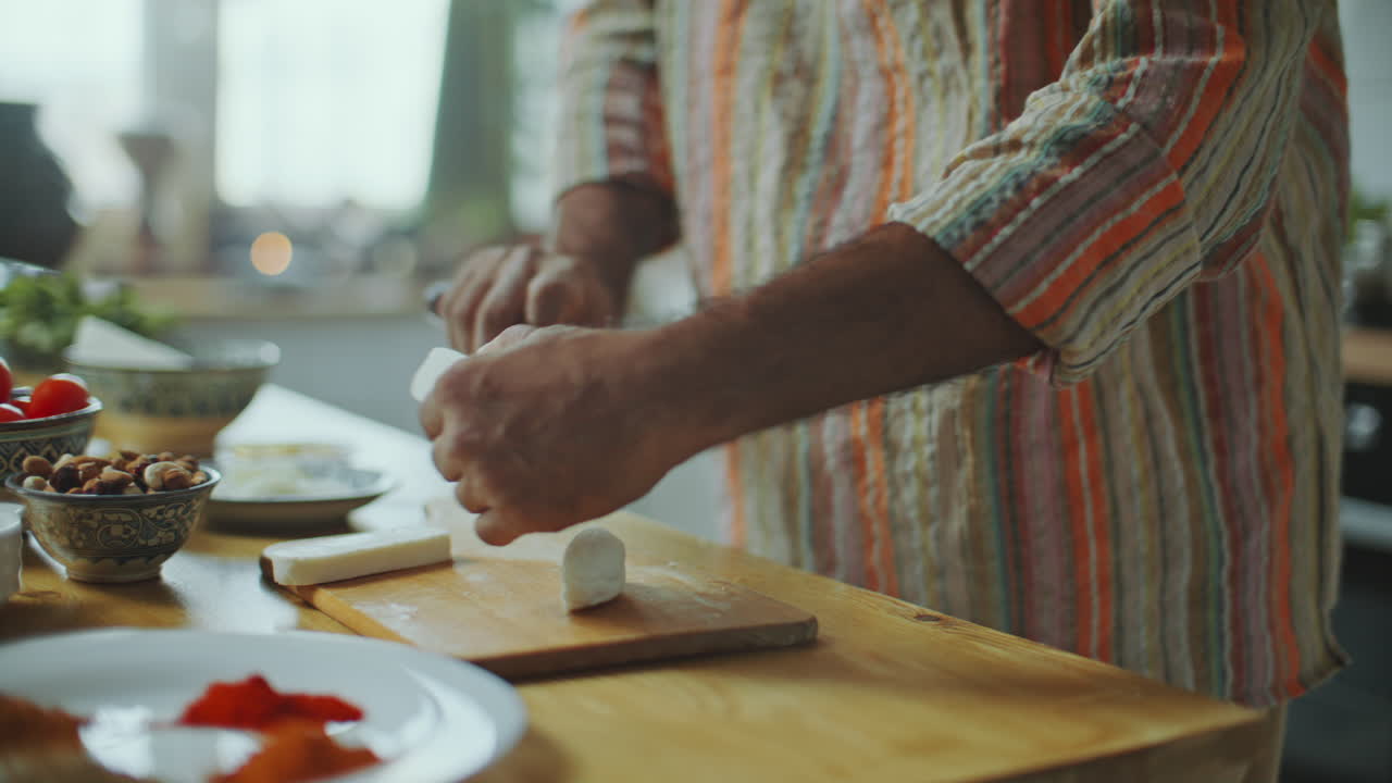 blogger de comida indio cortando queso paneer mientras cocina en la mesa de la cocina