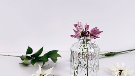 a still life of wilted flowers in a glass vase.