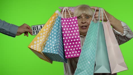 inscripción publicitaria viernes negro aparece junto a la abuela alegre con bolsas de compras