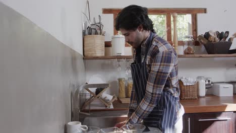 Profile-of-caucasian-man-washing-dishes-in-kitchen,-slow-motion