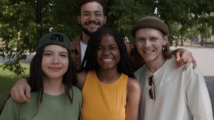 Groupe diversifié de jeunes amis s'étreignant et riant en extérieur